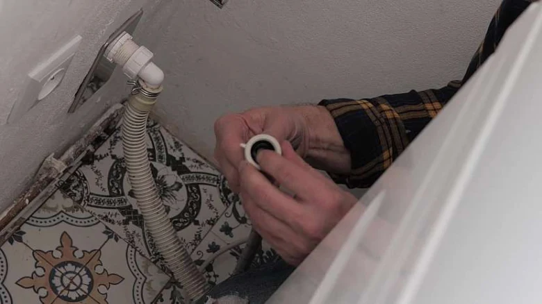 Ruční instalace zátky pro zapojení pračky do kanalizace.