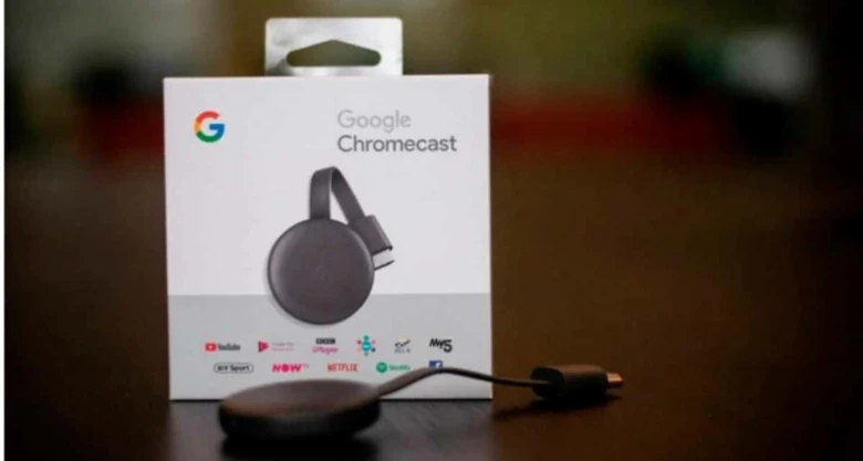 Kabelový přehrávač Google Chromecast v krabičce vedle samotného zařízení.