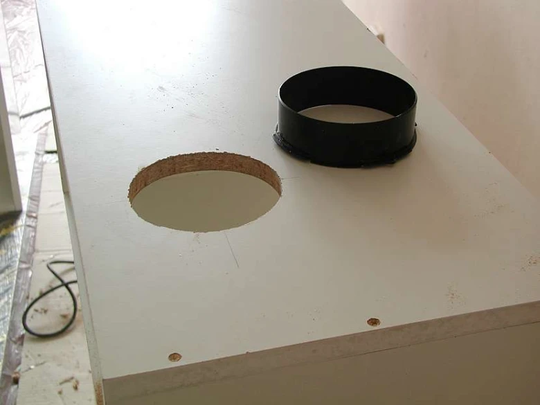 Černý plastový prstenec pro instalaci odsavače do bílé desky.