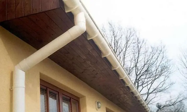 White plastic gutter pipe system on house eaves with downspo