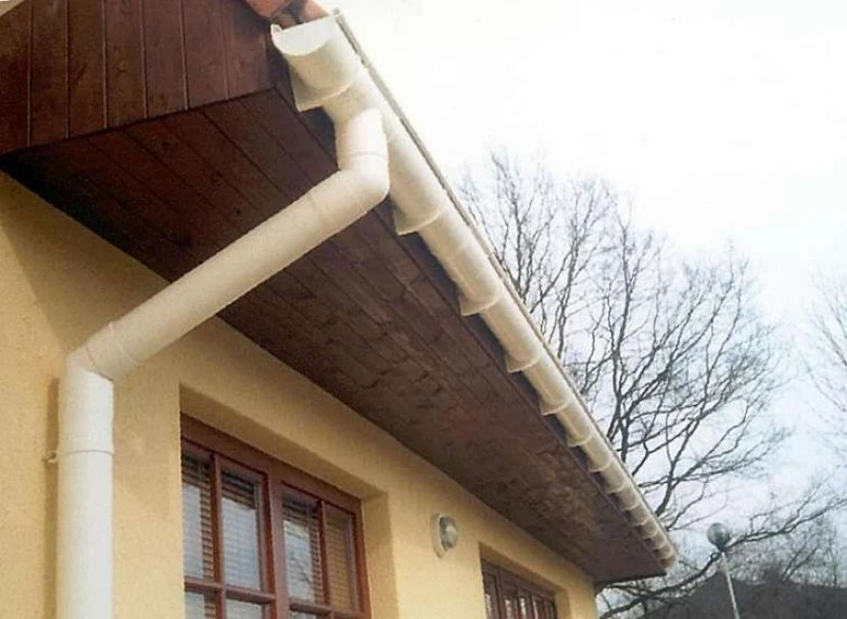 White plastic gutter pipe system on house eaves with downspo