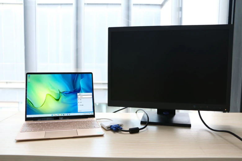 Laptop připojený k monitoru přes adaptér pro streamování obsahu.