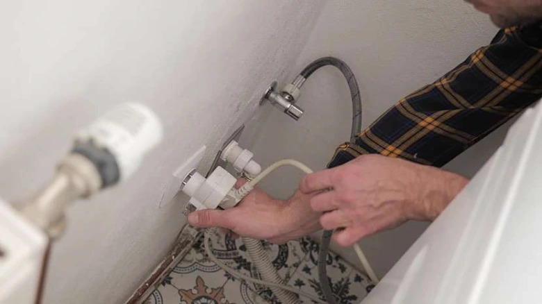 Instalace vodovodních vývodů pro pračku za stěnou v koupelně.