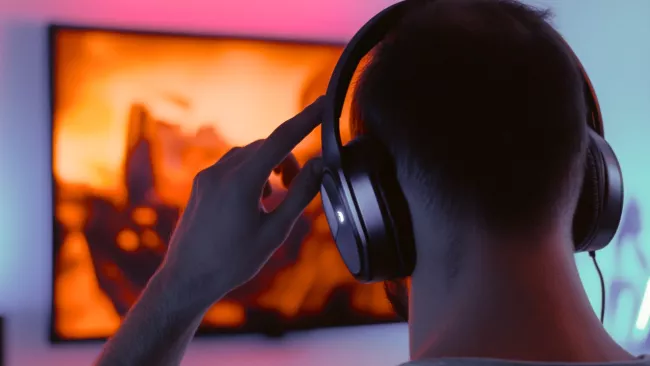 Muž s bezdrátovými sluchátky sleduje televizi.