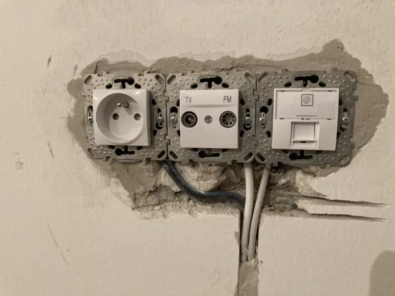 Instalace elektrických zásuvek v zdi s viditelným vedením.