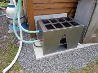 Nerezový ohřívač bazénu na dřevo s připojenými hadicemi.