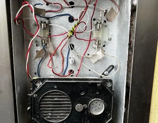 Vnitřní zapojení starého elektrického zvonku s dráty a transformátorem.