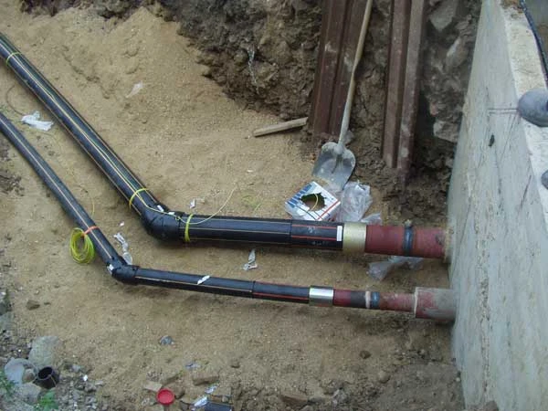 Černé potrubí NPVC položeno v jámě u betonového základu.