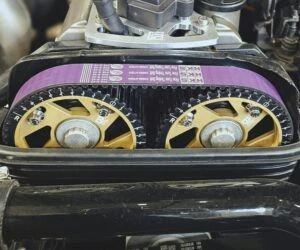 Fialový řemen na žlutých kladkách v motoru automobilu.