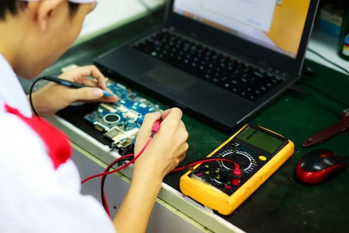Technik používá multimetr k měření na desce notebooku