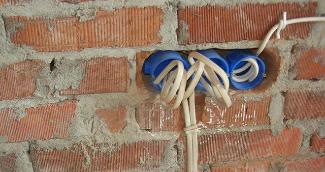 Bílá elektrická kabeláž v modrých zásuvkách ve zdivu