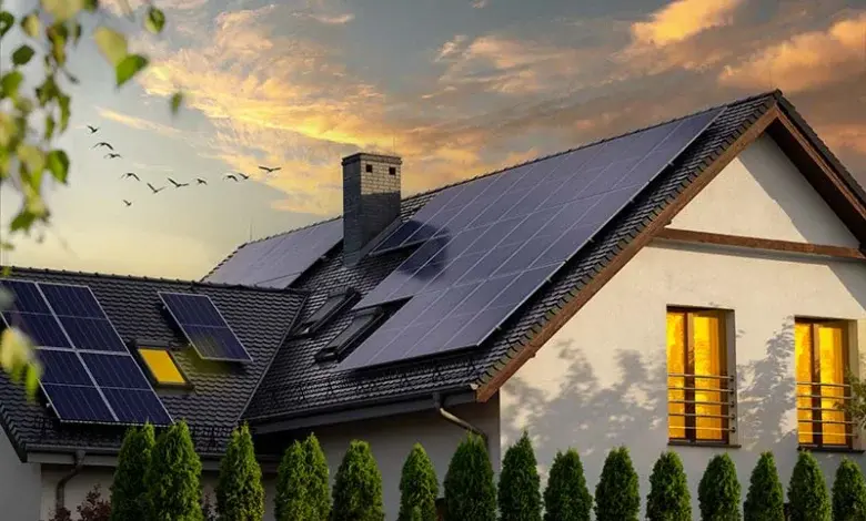 Dům s fotovoltaickými panely na střeše při západu slunce.