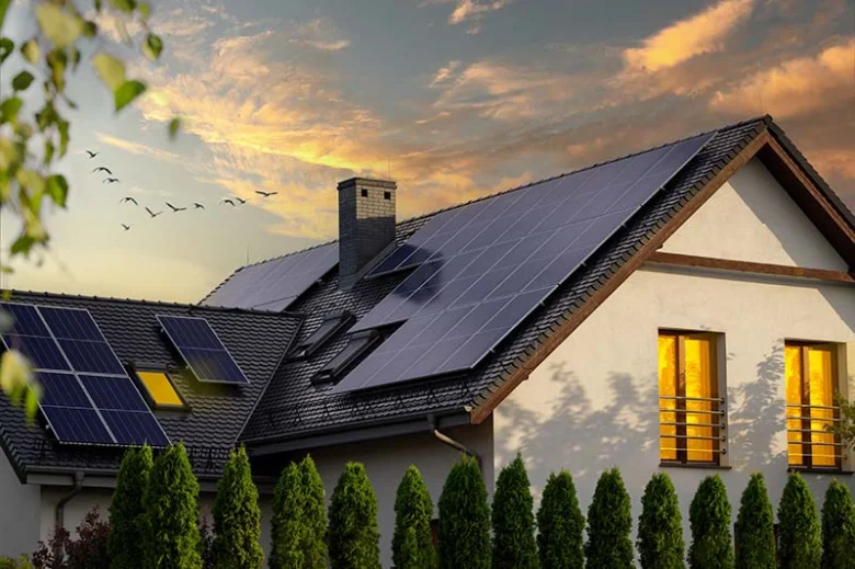 Dům s fotovoltaickými panely na střeše při západu slunce.