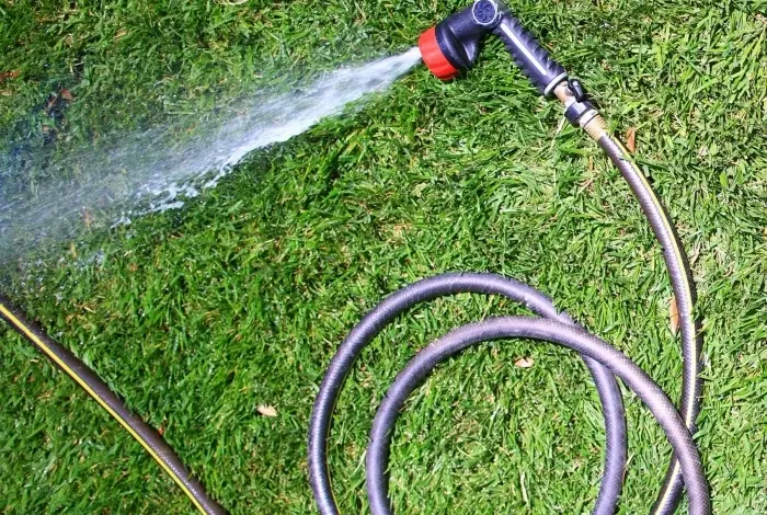 Hadice s rozprašovačem vody na trávníku.