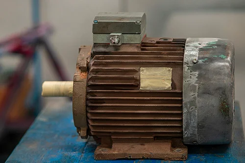 Rusty elektromotor na modré plošině pro technickou opravu.