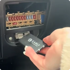 Ruka drží diagnostický nástroj u pojistkového boxu pro kontrolu elektrického systému.