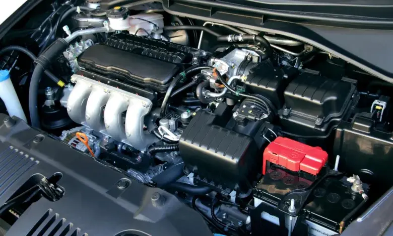 Motorový prostor automobilu s viditelnou baterií a hadicemi.