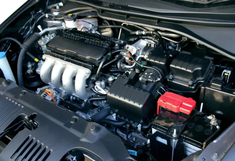 Motorový prostor automobilu s viditelnou baterií a hadicemi.