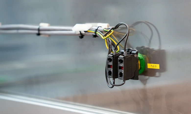 Černé elektrické konektory s barevnými vodiči na průmyslovém zařízení.