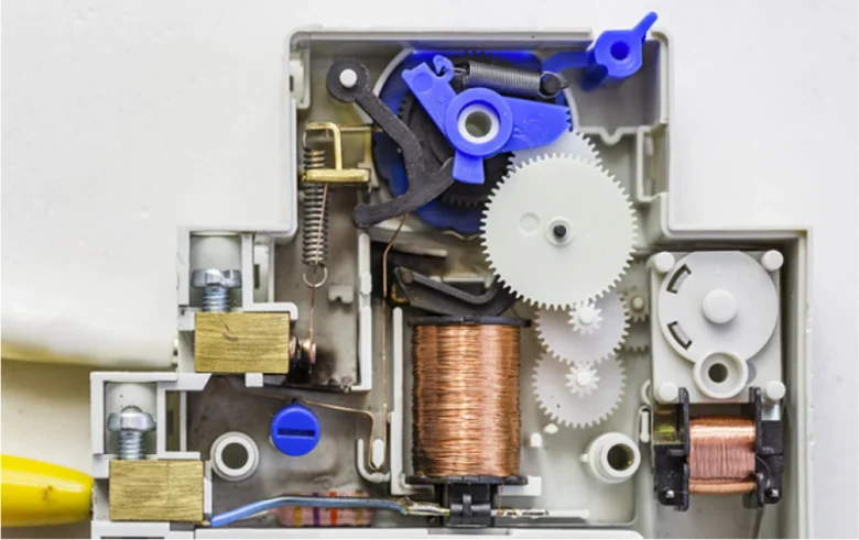 Vnitřní mechanismus elektromagnetického relé s cívky a převody.
