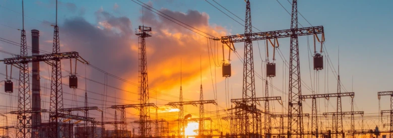 Silueta elektrárny s vysokým napětím na západ slunce.