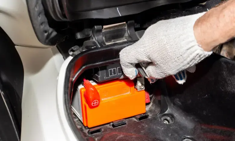 Ruka připojuje nabíjecí kabely k gelové automobilové baterii.