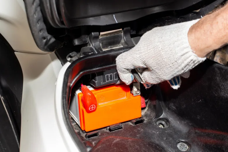 Ruka připojuje nabíjecí kabely k gelové automobilové baterii.