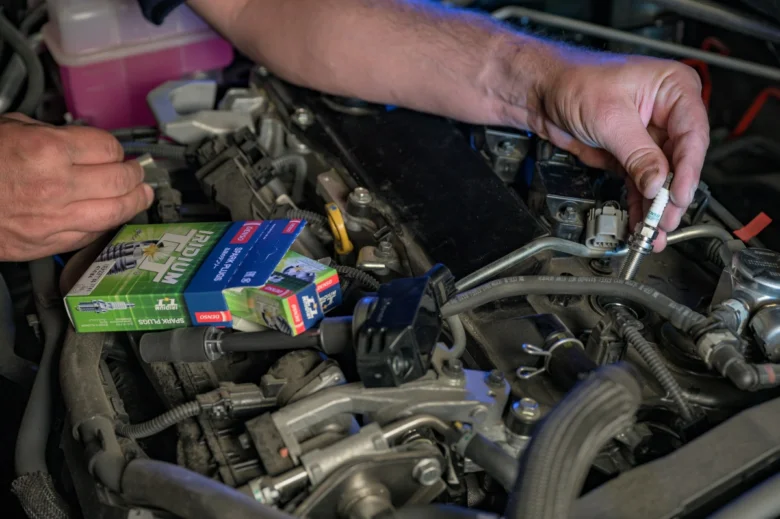 Mechanik montuje novou svíčku do motoru auta.