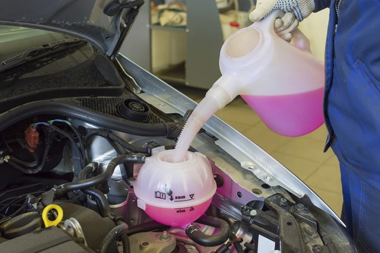 Mechanik nalévá růžovou nemrznoucí směs do rozšiřovací nádrže.