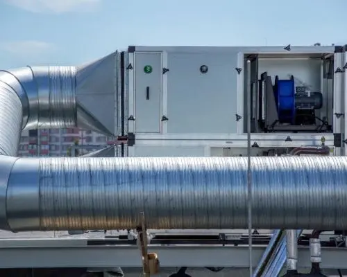 Mechanické větrací zařízení s potrubím na střeše budovy.