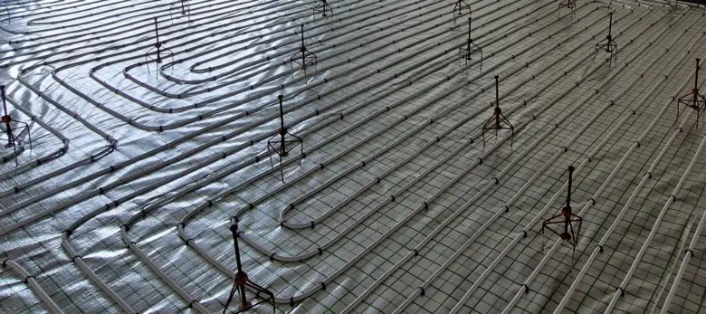 Instalace potrubí podlahového topení na izolaci s mřížkou.