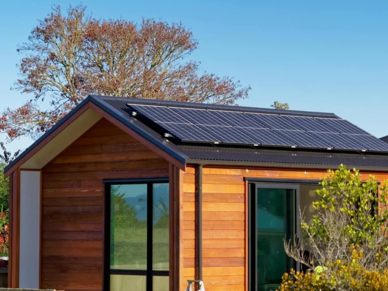 Dům s fotovoltaickými panely na střeše pod modrou oblohou.