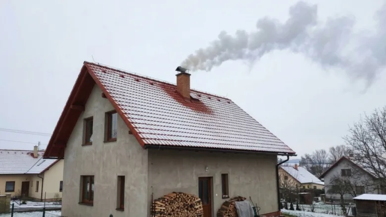 Dům s komínem vydávající kouř v zimě - příklad kondenzace.
