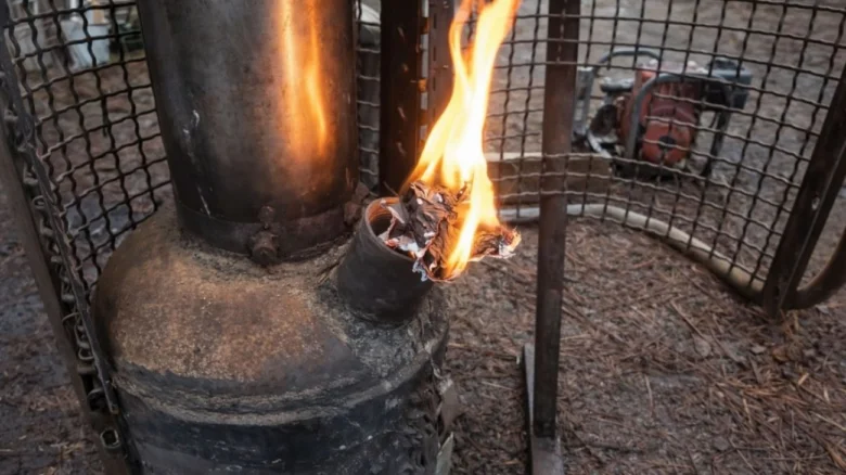 Zapálený dřevopec s hořícími papírovými úlomky na bočním výfuku.