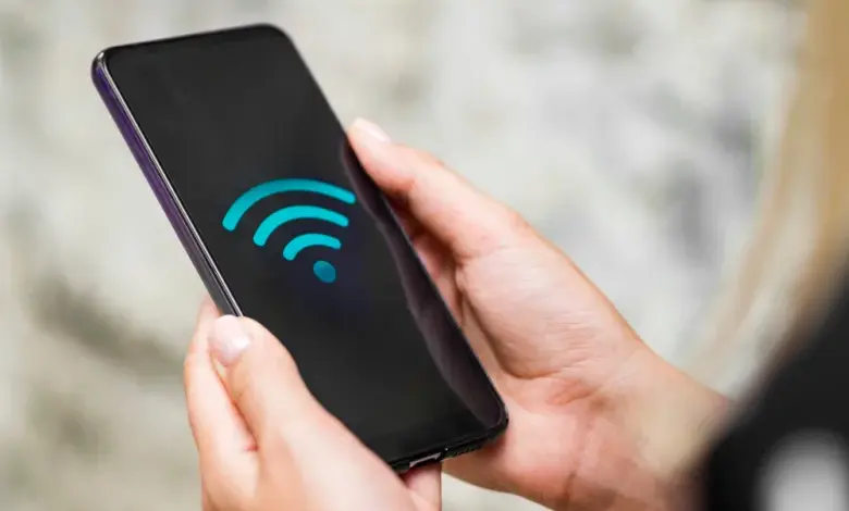 Ruka drží chytrý telefon s ikonou bezdrátového připojení.