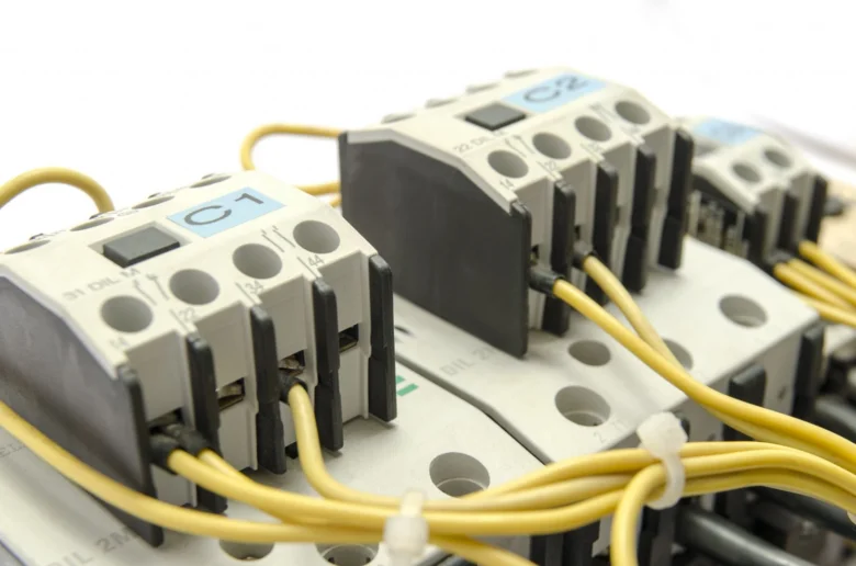 Žluté vodiče připojené na elektrické kontakty v rozvaděči.