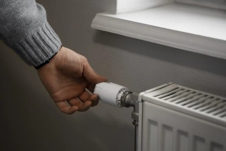 Ruka montuje termostatický ventil pro připojení radiátoru k topení.