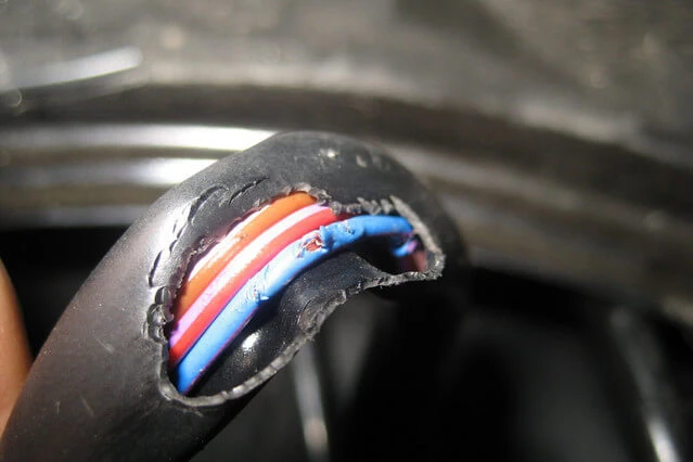 Přerušený kabel s viditelnými vodiči uvnitř poškozeného izolace.