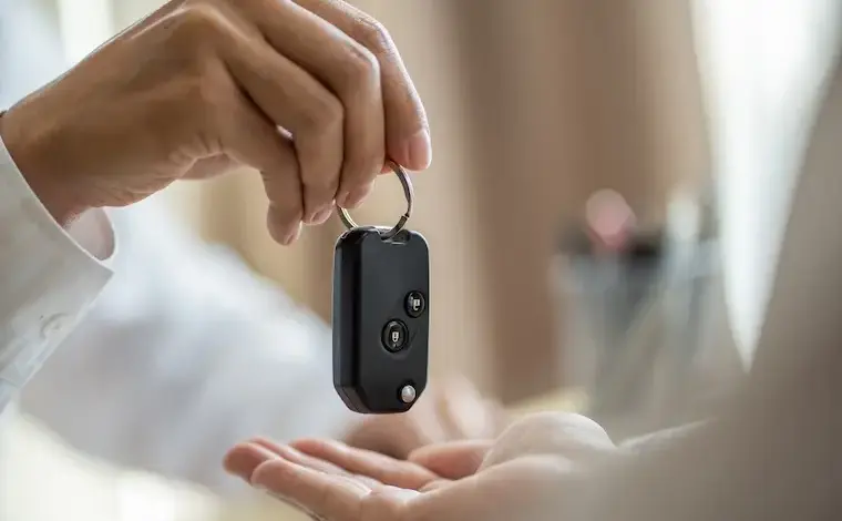 Ruční předání černého dálkového ovládání automobilu.