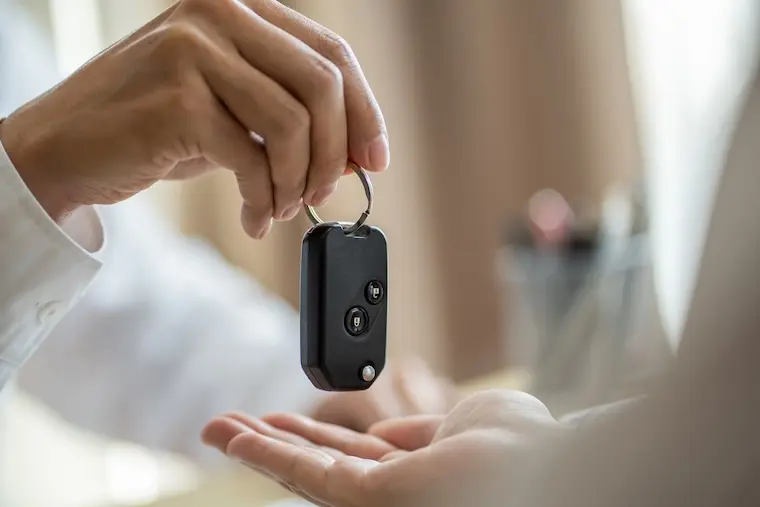 Ruční předání černého dálkového ovládání automobilu.