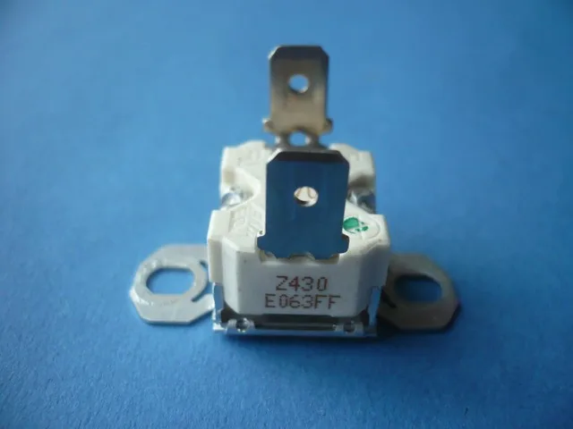 Elektrický spínač nebo relé s kovovými kontakty na modrém pozadí.