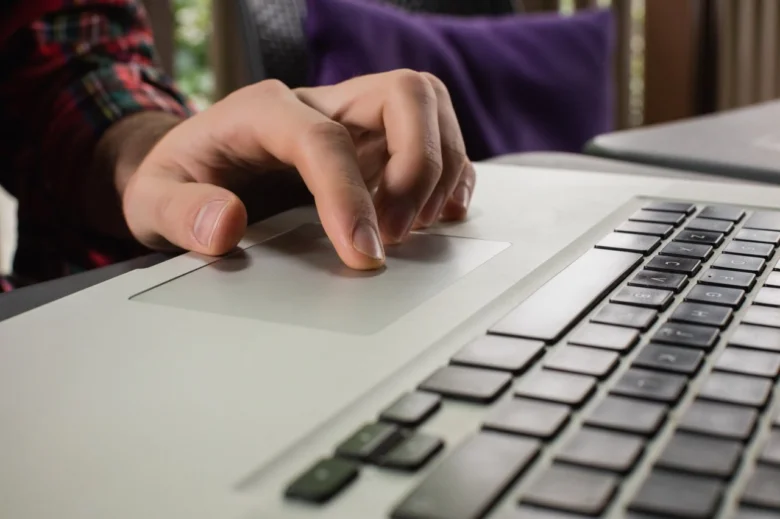 Ruka používá touchpad na notebooku pro ovládání.
