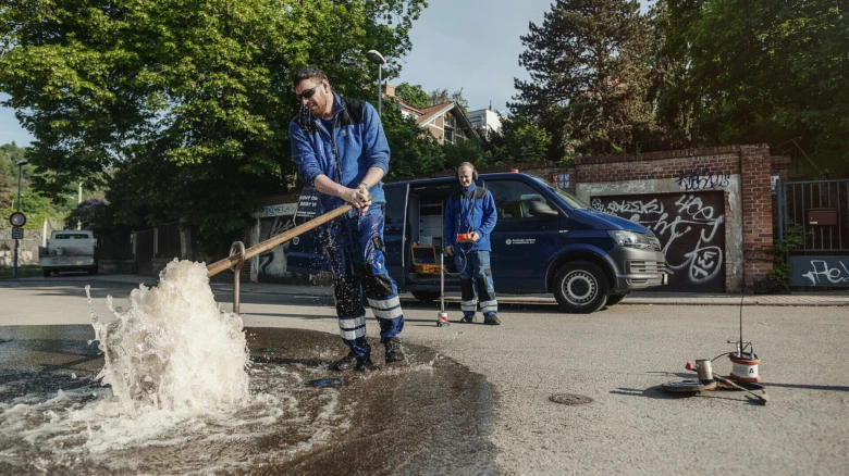Montér opravuje prasklý vodovod na ulici.