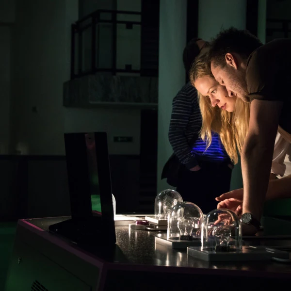 Dva lidé zkoumají elektronické komponenty pod skleněnými kupolemi.