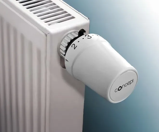 Bílá termohlavice na bílém radiátoru pro regulaci teploty.