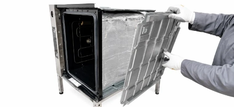 Technik odstraňuje dveře trouby pro výměnu topného tělesa.
