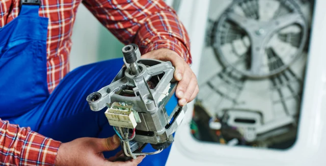 Technik drží rozložený elektromotor vedle ventilátoru v přístroji.