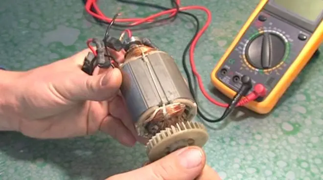 Ruční testování elektromotoru multimetrem s červenými a černými sondami.