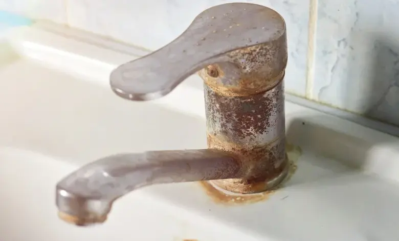 Rozbitý kohout s rezivou vrstvou na vodovodním potrubí.