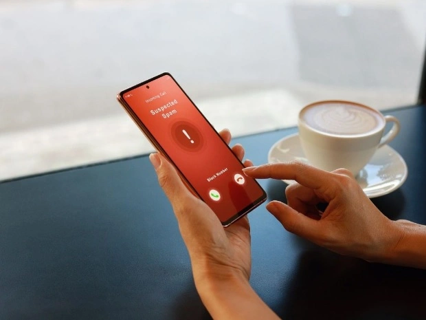 Ruka drží telefon s upozorněním na podezřelý spamový hovor.